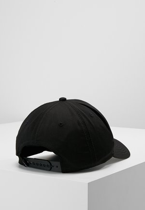 Black adjustable baseball cap resting on a white surface, shown from the back with a snapback strap visible.