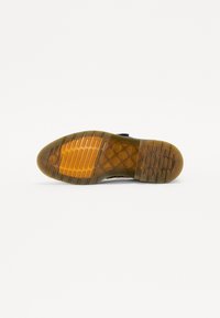 Zwarte sneakersole met een gestructureerd design. Heldere rubberen tussenzool en een gumkleurige rubberen buitenzool met horizontale en verticale groeven.