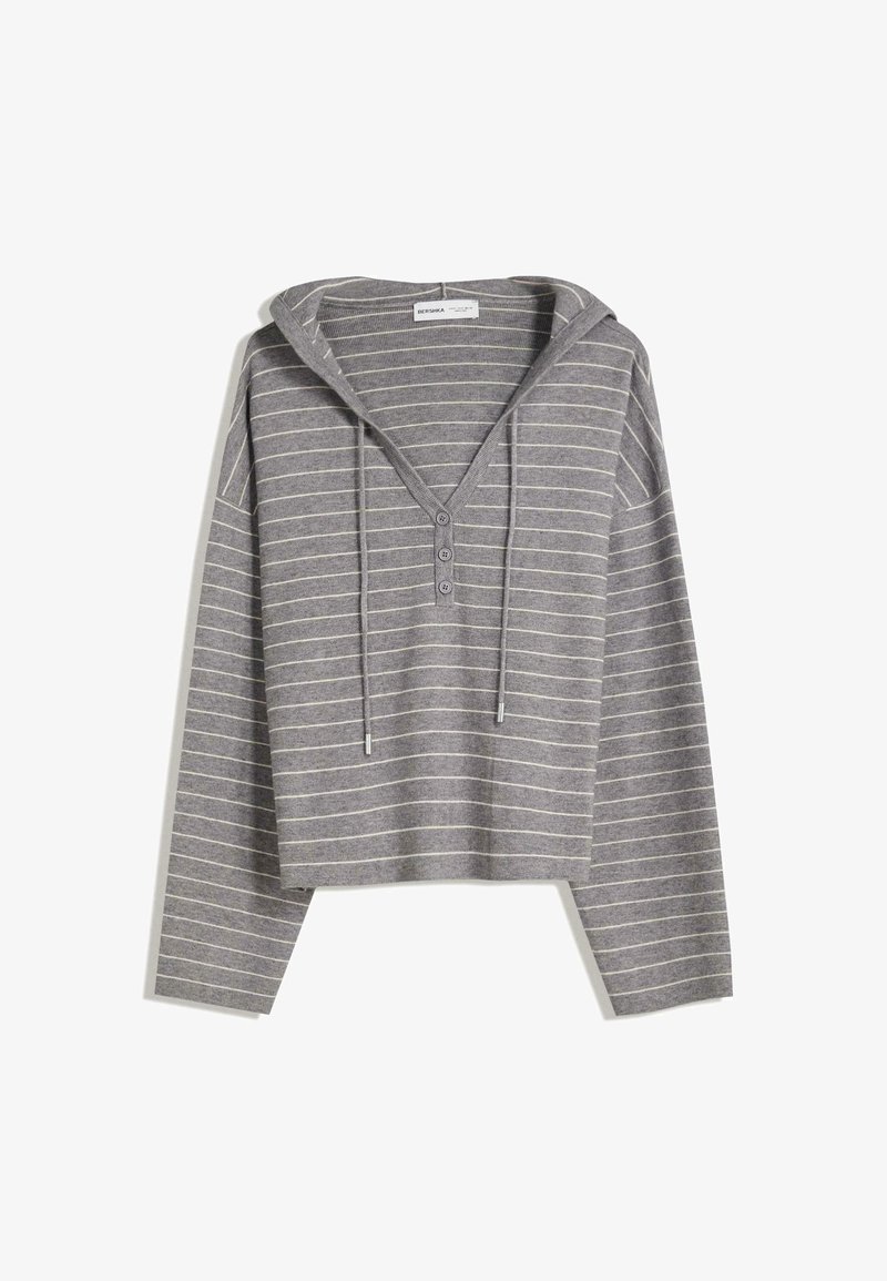 Siva skraćena kapuljača s tankim bijelim horizontalnim prugama, tri gumba na prsima i vezicama na kapuljači.