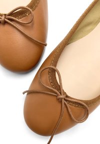 Bailarinas de cuero marrón con punta redonda y un ribete de tela texturizada. Presentan un lazo decorativo en la parte delantera.