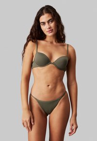 Conjunto de bikini verde oliva que incluye un sujetador moldeado con tirantes finos y un fondo tipo tanga a juego, hecho de una tela suave y elástica.