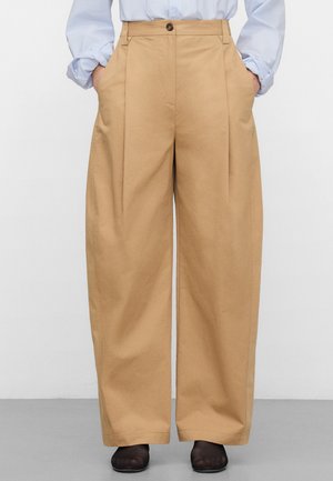 Weit geschnittene Hosen aus beige Baumwolle mit vorderen Falten, Seitentaschen und einem einzelnen Knopfverschluss an der Taille.