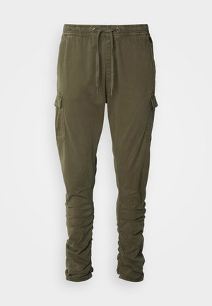 Ελαιόχρωμο cargo παντελόνι με ελαστική μέση, κορδόνι, πλαϊνές τσέπες και στενές γάμπες. Φτιαγμένο από μαλακό, υφασμάτινο ύφασμα.