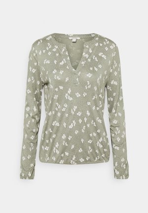 Long-sleeve blouse in olive green with a V-neck, featuring a floral pattern and dotted texture throughout. Soft, lightweight fabric.