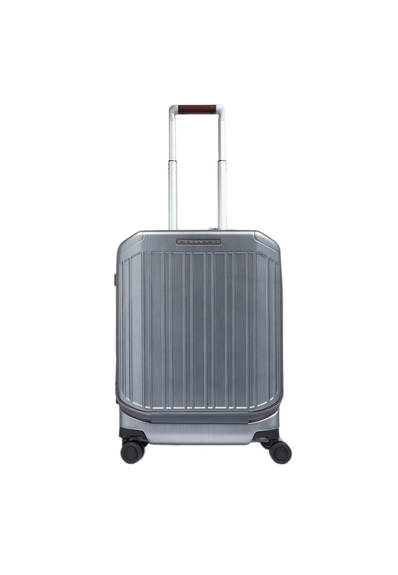 Silberner Hartschalenkoffer mit vertikalen Rillen, ausziehbarem Griff und vier Rollen. Metallische Oberfläche mit robuster Textur und abgerundeten Kanten.