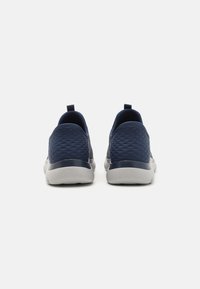 Navy slip-on shoes with textured fabric uppers, a smooth heel counter, and white rubber soles; features a practical rear pull tab.