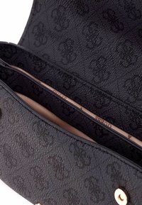 Borsa nera in tessuto con motivo a monogramma, dotata di un interno chiaro e due scomparti, chiusa da una chiusura a bottone.