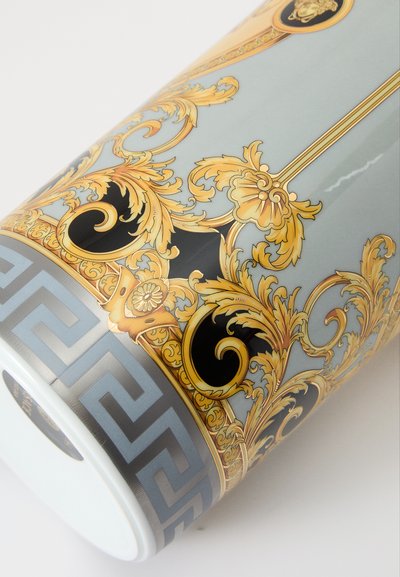 Recipiente cerâmico com superfície azul claro brilhante, padrões florais ornamentados em dourado e preto, e uma faixa geométrica cinzenta na base.