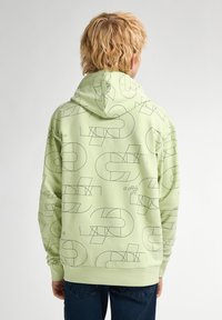 Sudadera verde claro con patrones geométricos negros, de mangas largas y capucha con cordones; tiene un corte relajado y puños acanalados.