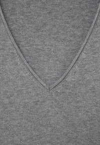 Gros plan sur un tissu en tricot gris avec un détail de couture en V.