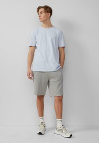 Lichtblauwe katoenen T-shirt, grijze jersey shorts en witte sneakers met grijze accenten. De outfit heeft een minimalistisch ontwerp en een casual pasvorm.