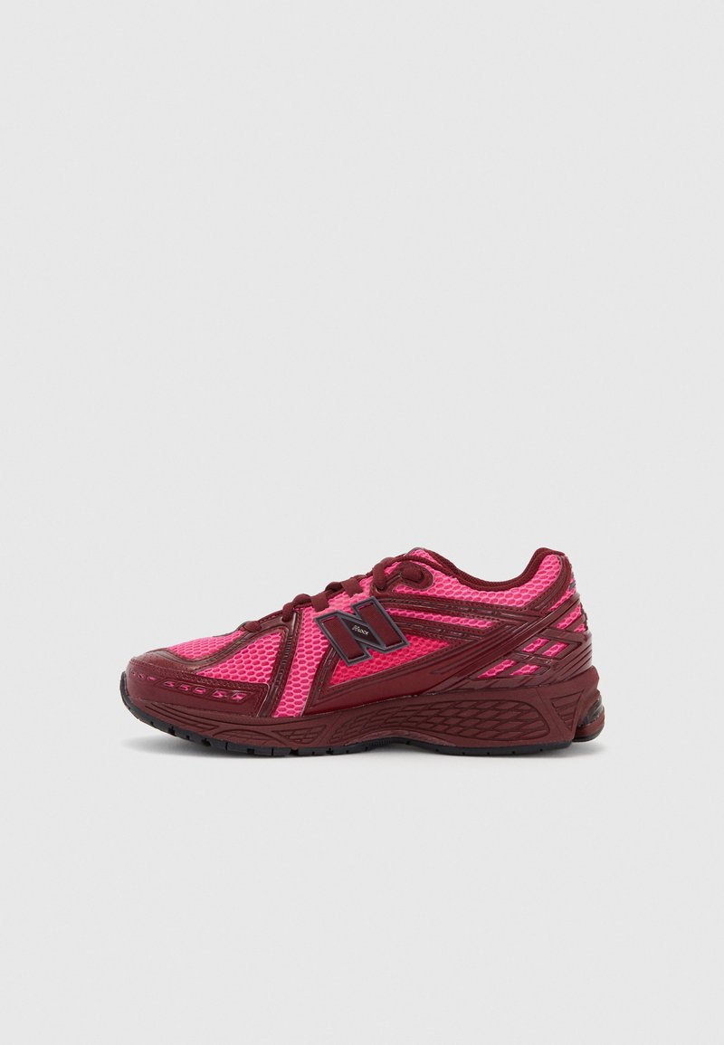 Red and pink athletic shoe with mesh upper, thick sole, padded collar, and contrasting accents for support and breathability.
