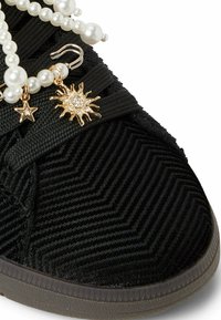 Czarne sneakersy z teksturowanego korduroju, ozdobione dekoracyjnym łańcuchem z pereł oraz złotymi charmsami w kształcie słońca i gwiazdy, na gumowej podeszwie.