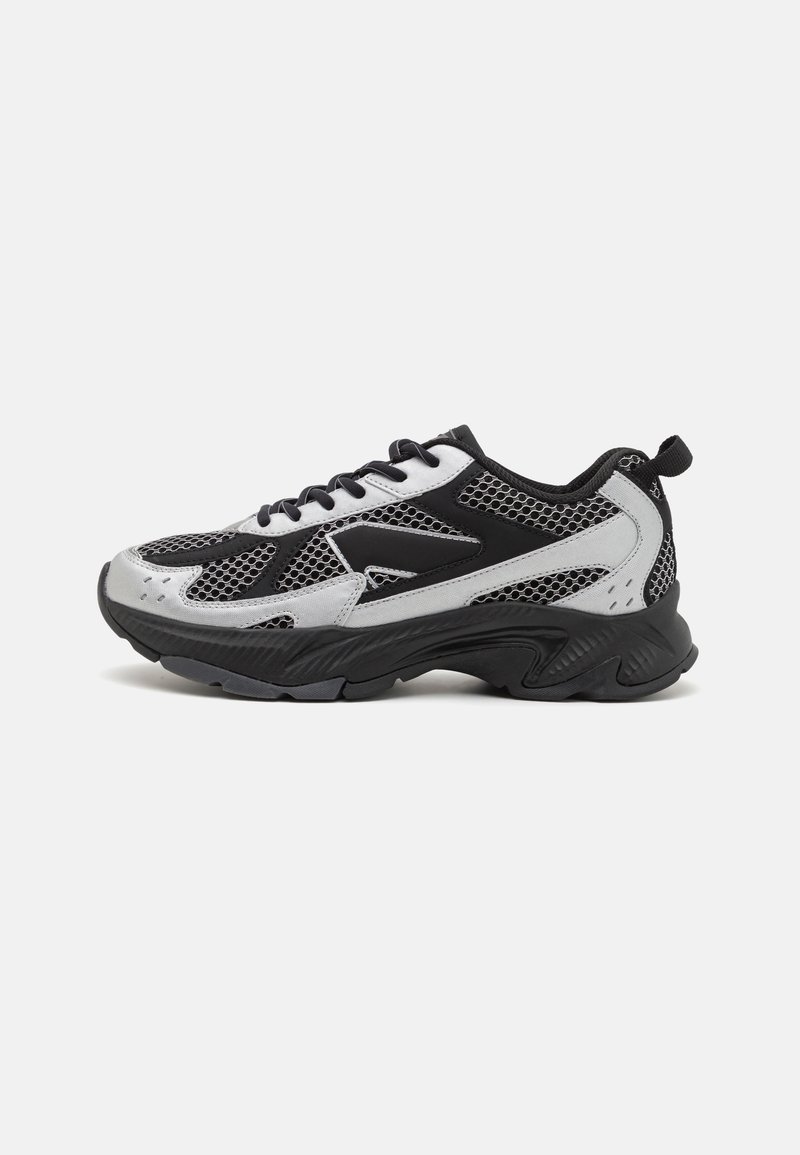 Black and silver athletic shoe featuring a mesh upper, rounded toe, textured sole, and lace-up design. Reinforced heel and pull tab are present.