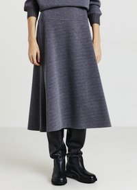 Grauer knie-langer Rock aus weichem Stoff mit glatter Textur, ausgestattet mit einem taillierten Bund und ausgestellter Silhouette, kombiniert mit schwarzen Stiefeln.