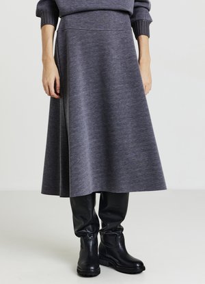 Gonna grigia al ginocchio realizzata in tessuto morbido con una texture liscia, caratterizzata da una fascia vita aderente e una silhouette svasata, abbinata a stivali neri.