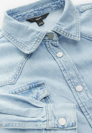 Helles blaues Denimhemd mit spitzem Kragen, silbernen Druckknöpfen und einer Brusttasche. Verfügt über einen weichen, strukturierten Stoff und hochgerollte Ärmel.