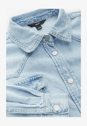 Lichtblauwe denimshirt met een puntkraag, zilveren drukknoopjes en een borstzak. Het shirt heeft een zachte, gestructureerde stof en opgerolde mouwen.