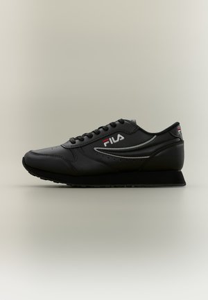Basket basse noire FILA à lacets, avec un logo sur le côté et une semelle épaisse, présentée de profil sur un fond uni.