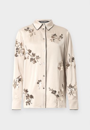 Beige Langarm-Hemd mit Knopfleiste, schwarzen Paspeln am Kragen und an den Manschetten, verziert mit braunen und goldenen, blumigen Paillettenmotiven.