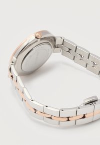 Μεταλλικό λουράκι ρολογιού από ασημί και ροζ χρυσό με στρογγυλή πίσω θήκη και κορώνα σε λευκό φόντο.