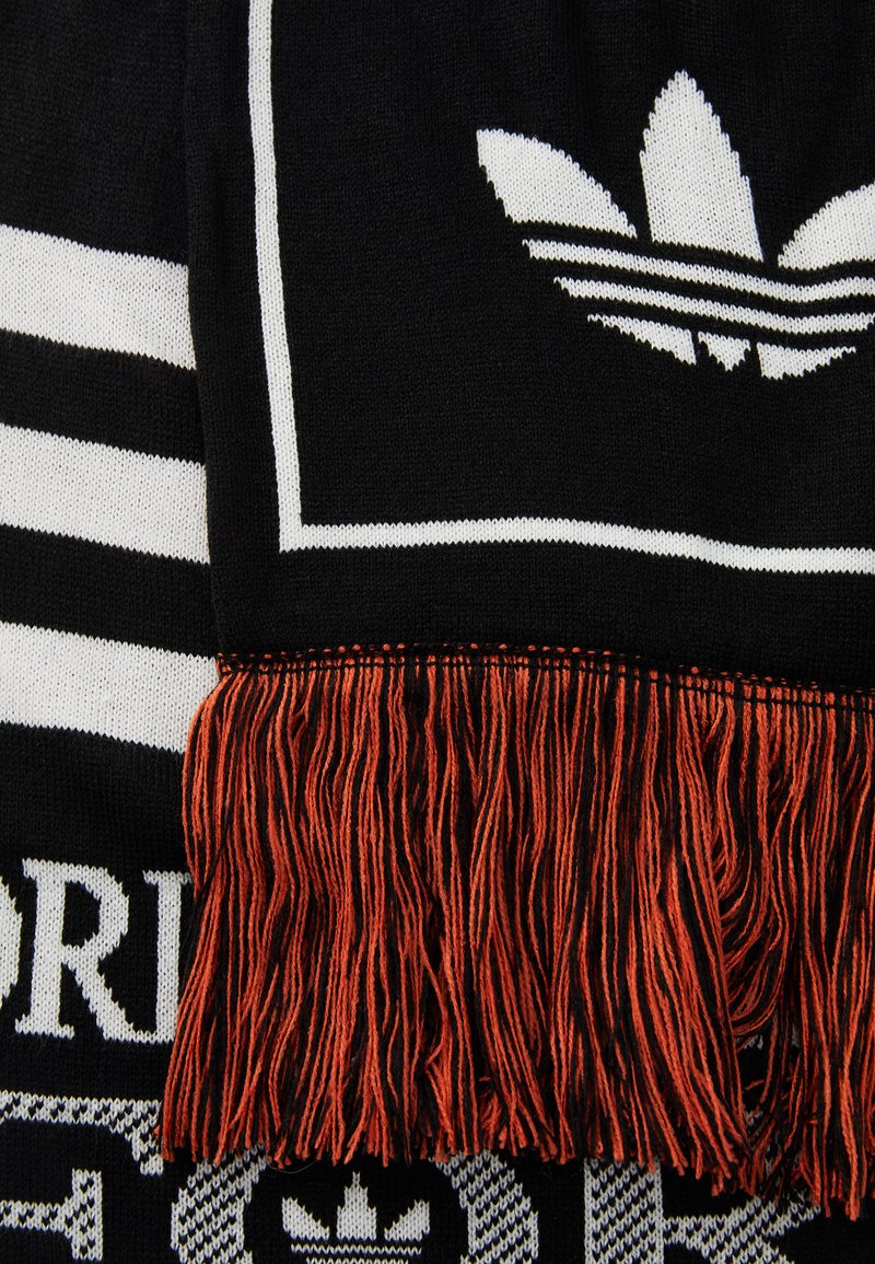 Black scarf featuring white stripes and a logo, with orange fringe at the bottom. Material appears knitted with a smooth texture.