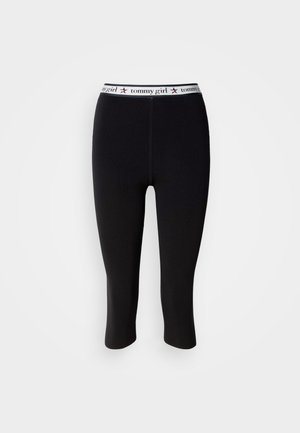 Black leggings with a tight fit and cropped length, featuring a white waistband with "tommy girl" text and red star accents.