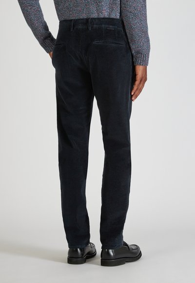 Granatowe spodnie z korduroy o prostym kroju, charakteryzujące się miękką teksturą, dwoma tylnymi kieszeniami oraz ręką noszącego w kieszeni.