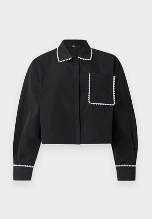 Chemise noire à manches longues et courte, dotée d'une poche avant, d'un col et de poignets ornés de perles blanches imitant des perles.