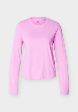 Ροζ αθλητική μπλούζα με μακριά μανίκια, στρογγυλή λαιμόκοψη και μικρό λευκό λογότυπο Nike κεντραρισμένο κάτω από τη λαιμόκοψη, εμφανίζεται σε απλό φωτεινό φόντο.