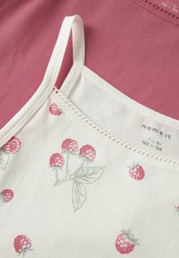 Weißes ärmelloses Oberteil mit Himbeerdruck und feiner Spitzenverzierung; kombiniert mit einem einfarbigen rosa Top darunter.