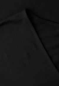 Sort stof med synlige syningsdetaljer langs foldede kanter, der viser tekstur og sømmeteknik.