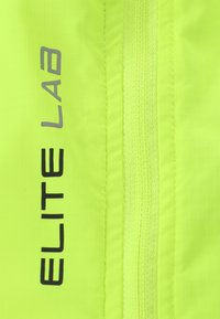 Helles gelbes Gewebe mit einem Rautenmuster. Enthält "ELITE" in Schwarz und "LAB" in Grau, neben einem passenden strukturierten Reißverschluss.