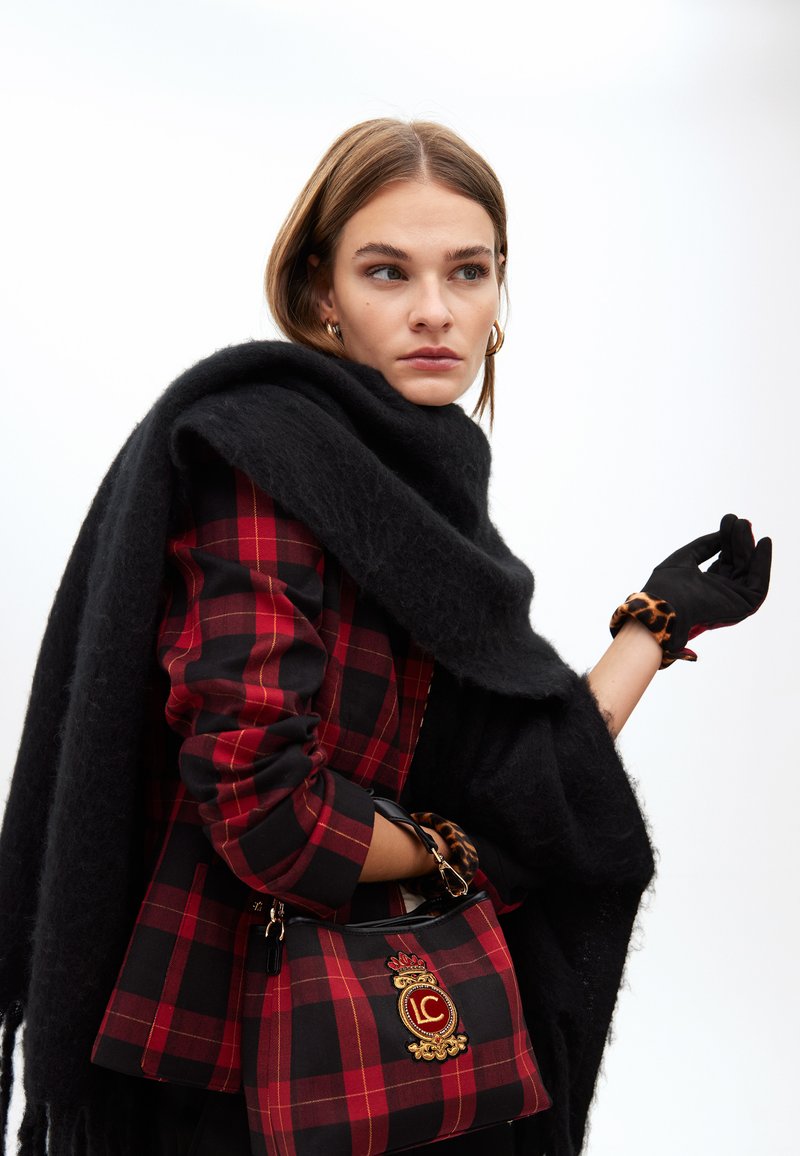 Röd och svart rutigt blazer med en texturerad svart scarf. Svarta handskar med leopardmönstrade detaljer. Svart handväska med gyllene emblem.