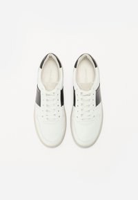 Sneakers bianchi con dettagli in pelle nera, punta tondeggiante, design con lacci e suole in gomma bianca testurizzata. Stile minimalista con linee pulite.