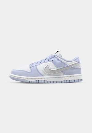 Nike Dunk Low sporta apavi gaiski zilā un baltā krāsā, ar korduroja un ādas materiāliem, gumijas zoli un klasiskām dizaina iezīmēm.