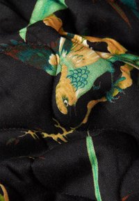 Bloemenpatroonde stof met levendige groene, gele en zwarte kleuren, met een soepele, satijnen uitstraling en een lichte glans.