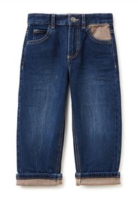 Jeans de denim azul oscuro con puños enrollados, tejido contrastante en el bolsillo derecho y detalles de costura dorada. Diseño clásico de cinco bolsillos.