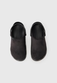 Par crnih slip-on Crocsa s teksturiranim ulošcima i prilagodljivim remenima na peti na jednostavnoj bijeloj pozadini.
