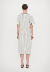 Pletený dvoudílný komplet s vertikálními černými pruhy na světlém pozadí. Tričko s krátkými rukávy a sukně ke kolenům, oboje s přímým střihem.