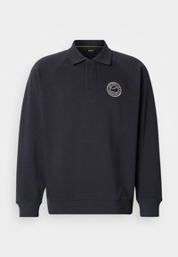 Μπλε ναυτικό πόλο φούτερ από μαλακό ύφασμα, με ριμπ κολάρο, μακριά μανίκια και κεντημένο λογότυπο στο στήθος.