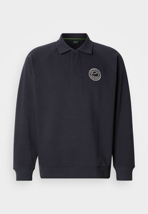 Meresinine polostiilis pusa, tehtud pehmest kangast, millel on soonikuga krae, pikad varrukad ja rinnal tikitud logo.