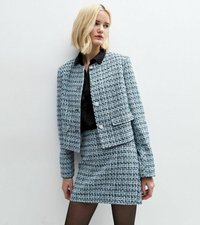 Blå och vit tweedjacka med en kortad design och silverknappar, i kombination med en matchande minikjol. Svart blus under.