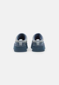 Blue athletic shoes with a textured mesh upper, rounded back, subtle silver accents, and a thick sole. Rubber outsole for traction.
