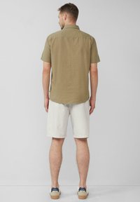 Olivgrünes kurzärmliges Hemd mit Button-down-Kragen, kombiniert mit hellbeigen Shorts und weißen Sneakers. Einfaches, strukturiertes Design.