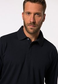 Marinblå långärmad pikétröja med klassisk krage, knäppning fram och textil med struktur för komfort och passform.