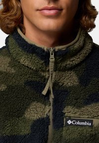 Giacca in pile con motivo mimetico verde e blu scuro, dotata di colletto alto, zip a quarto e logo Columbia sul davanti.
