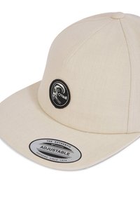 Beige justerbar baseballcap lavet af stof. Har en sort cirkulær logo-patch og et skinnende metalmærke, der siger "The Authentic Adjustable."