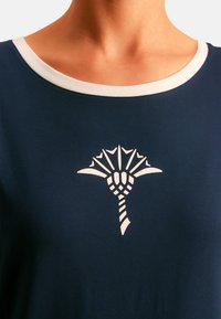 Marineblaues T-Shirt mit weißem Rundhalsausschnitt. Verziert mit einer zentralen Grafik einer stilisierten Blume mit linearem Stiel und strukturierten Details.