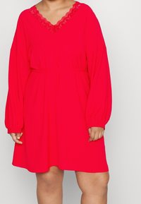 Rode jurk met lange poffende mouwen, V-hals met kantafwerking, getailleerde taille en een relaxte pasvorm. Gemaakt van zachte, lichtgewicht stof.